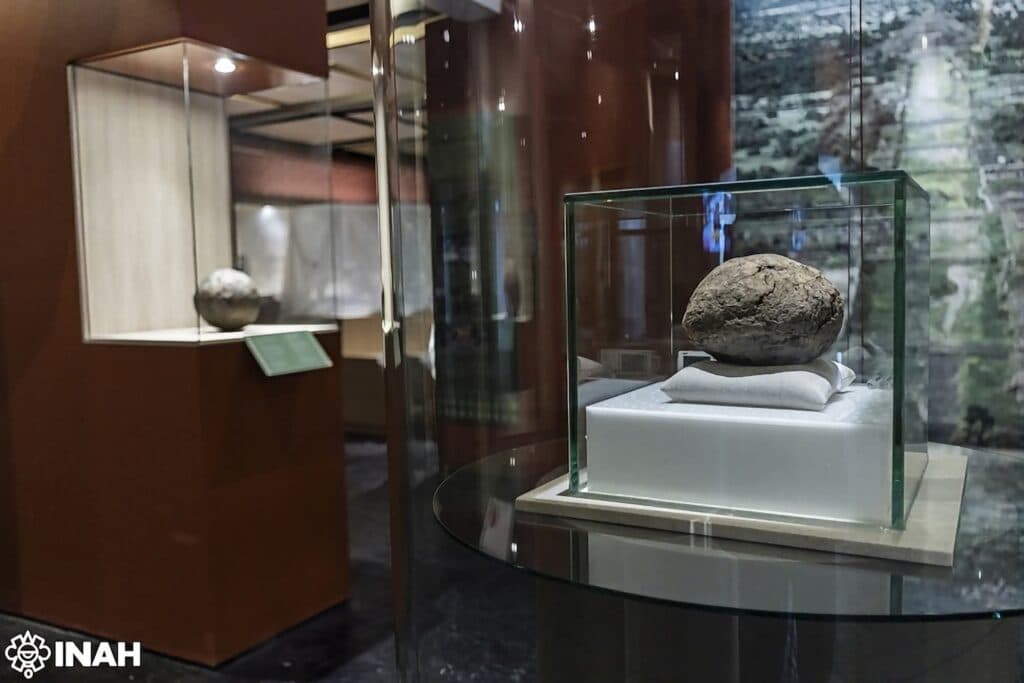 Pelota de hule de 3,600 años exhibida en vitrina en la exposición Hule ritual en la Zona Arqueológica de Teotihuacan.