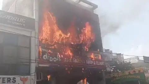 Incendio en un edificio de tres niveles en Lucknow, India, con llamas intensas que consumen la fachada del instituto educativo.