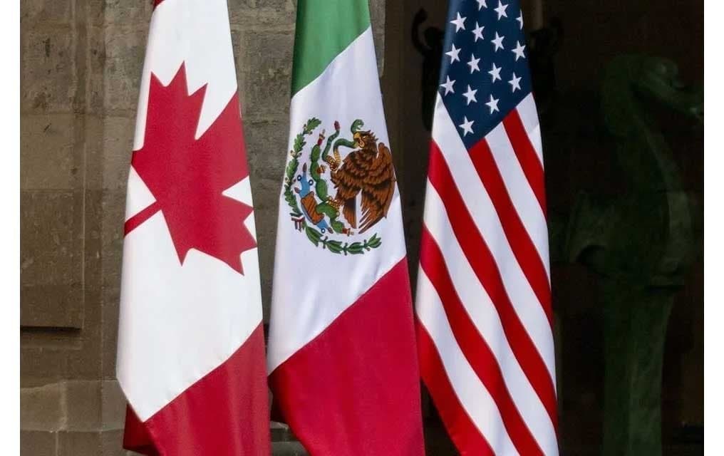 Banderas de México, Estados Unidos y Canadá en un evento relacionado con el T-MEC, simbolizando la cooperación comercial entre los tres países.