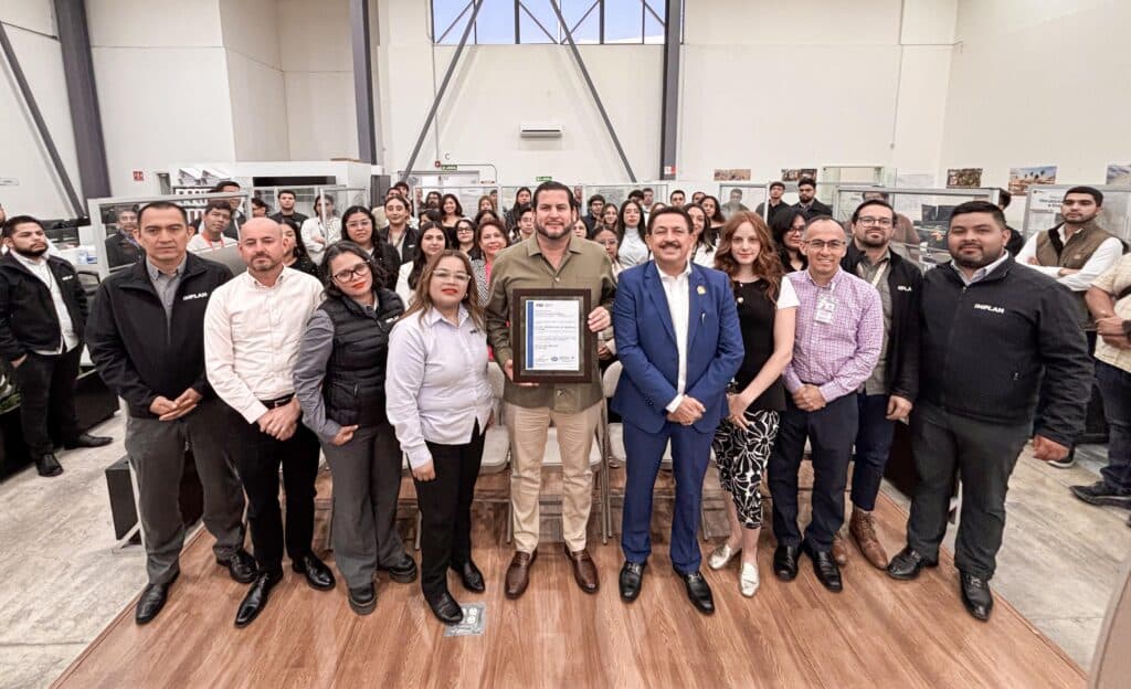 Ismael Burgueño Ruiz presenta la certificación ISO 9001:2015 al IMPLAN, rodeado de colaboradores en Tijuana.