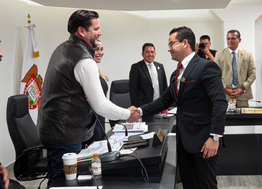 El presidente municipal Ismael Burgueño Ruiz estrecha la mano de un miembro del Cabildo durante la sesión extraordinaria en Tijuana.