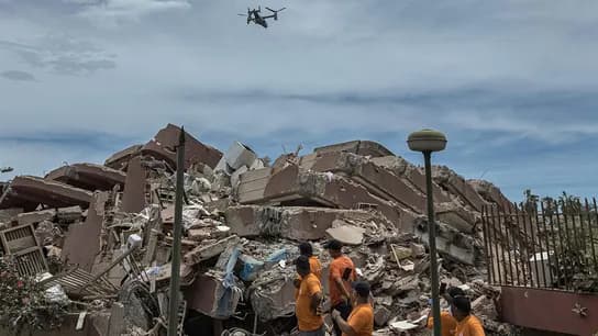 Rescatistas en la zona afectada por el terremoto en Venezuela observan un dron sobre los escombros de un edificio colapsado.