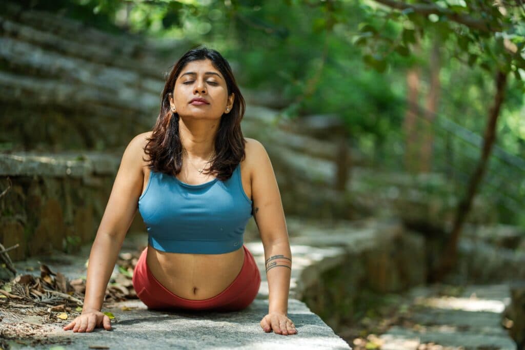 Mujer practicando yoga en un entorno natural, enfocada en su respiración, reflejando los beneficios de esta disciplina para la salud mental.