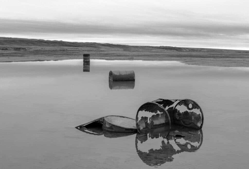 Barriles oxidados en un entorno acuático reflejan preocupaciones sobre residuos radiactivos en el océano Atlántico.