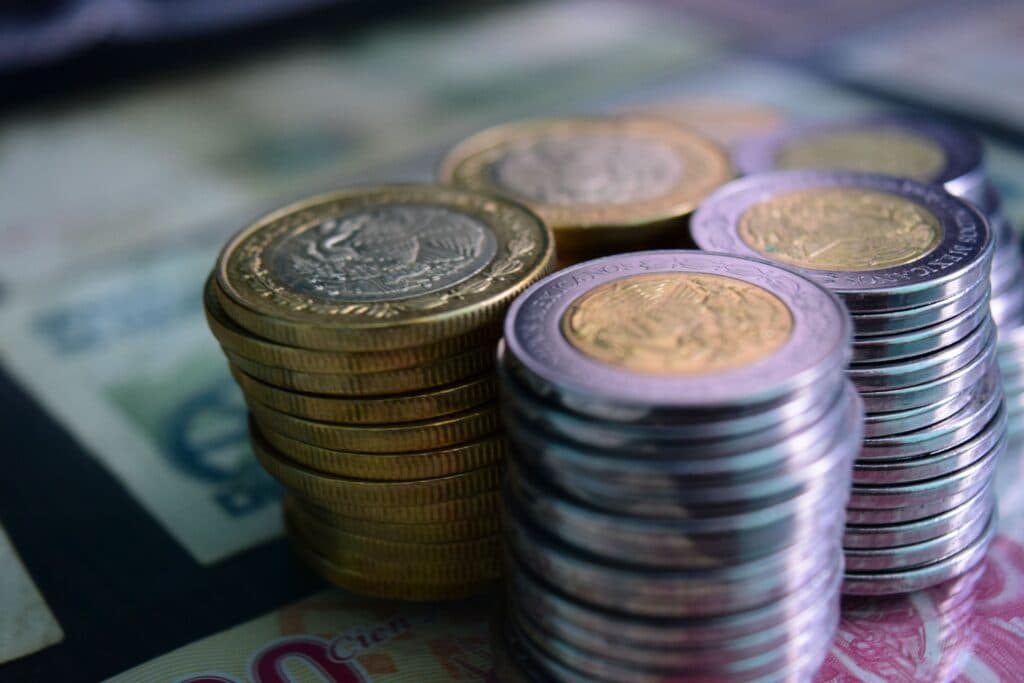 Monedas y billetes mexicanos apilados, representando la economía y la inflación en México.