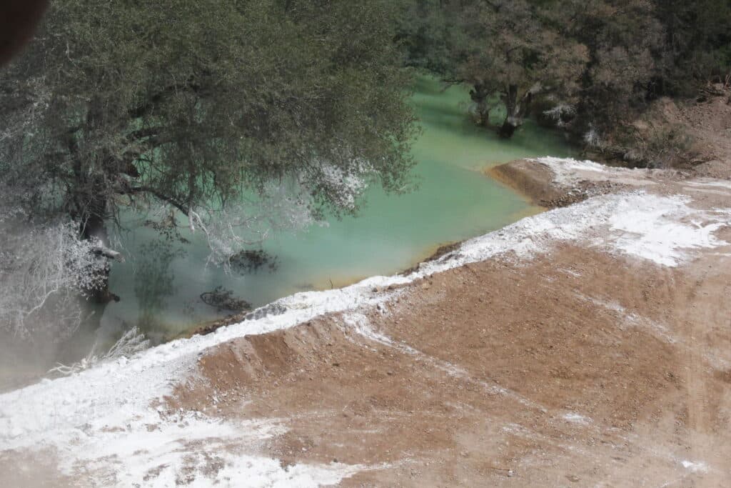 Contaminación visible en el Río Sonora, con aguas de color verde y sedimentos en la orilla, tras el derrame de Grupo México.
