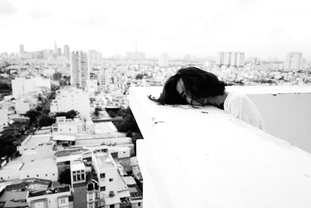 Joven con cabello oscuro se asoma sobre un borde en un edificio, reflejando la crisis de suicidios en México en 2025.