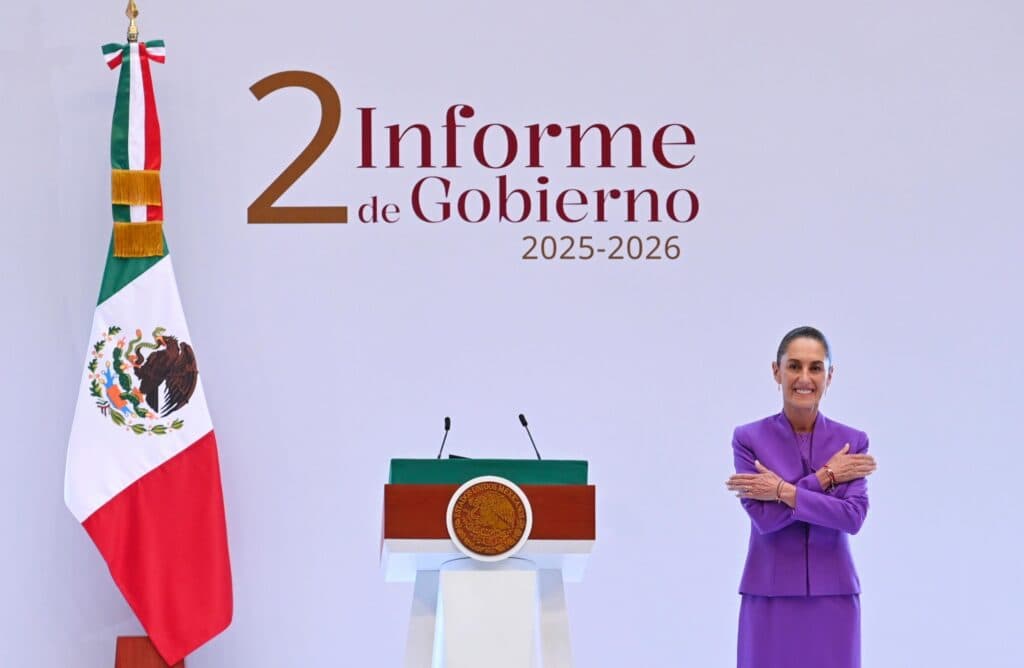 Claudia Sheinbaum presenta su Segundo Informe de Gobierno 2025-2026 en Palacio Nacional, con bandera y podio de fondo.